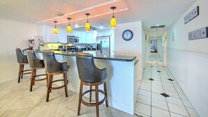 A kitchen with a central island, bar stools, and pendant lighting.