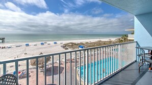 A balcony with a view of a beach and a pool.