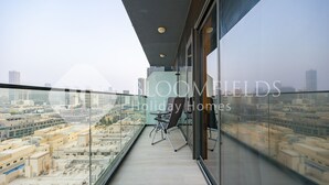 A balcony with a city view, a chair, and a table. - Bloomfields Spacious 1BR Bloom Tower (Dubai)