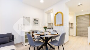 A modern dining area with a round table, grey chairs, and a white cabinet with glass doors. - Bloomfields Spacious 1BR Bloom Tower (Dubai)