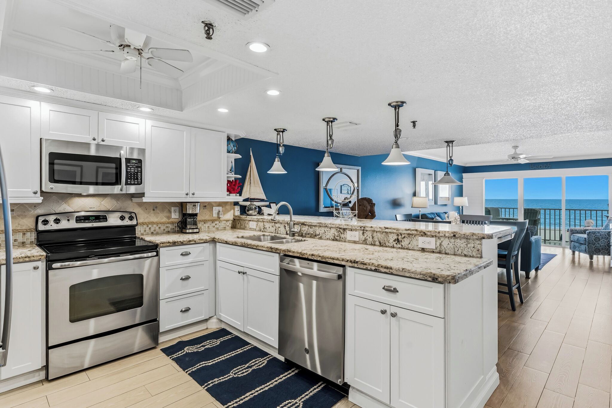 A modern kitchen with white cabinets, stainless steel appliances, and a large island.