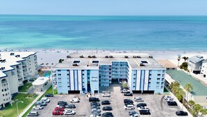 A hotel with a pool, parking lot, and beach view.