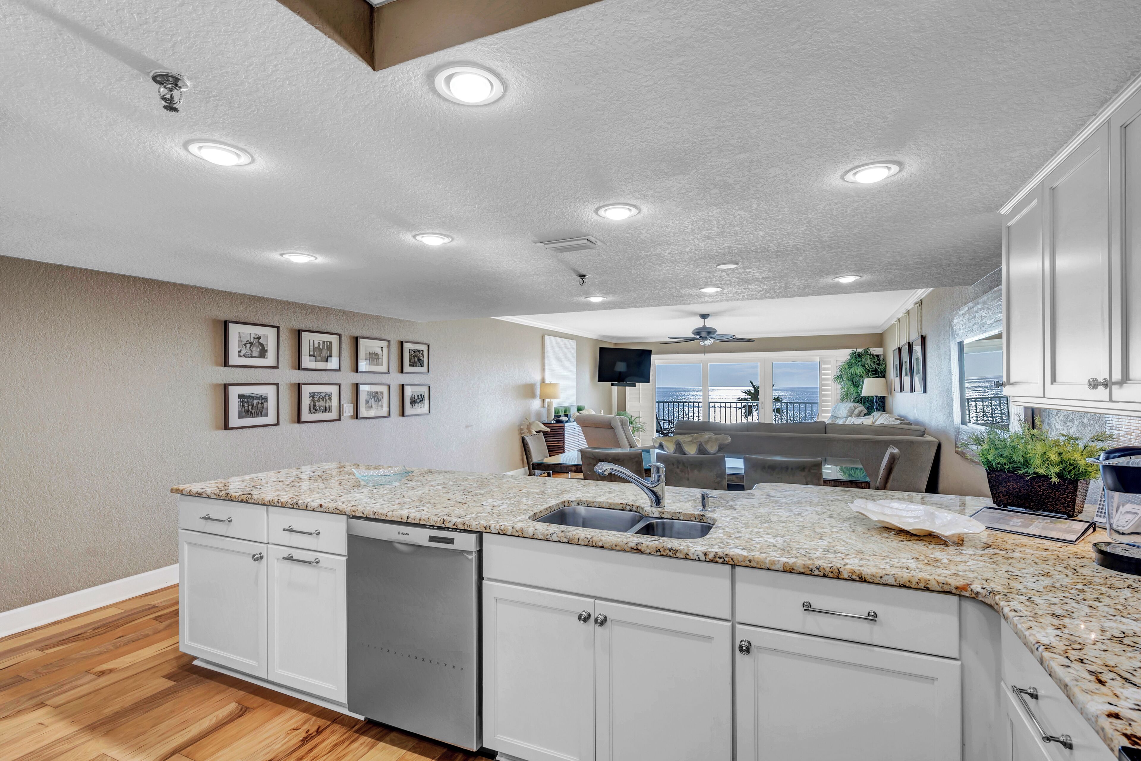 A modern kitchen with white cabinets, granite countertops, and a built-in dishwasher.