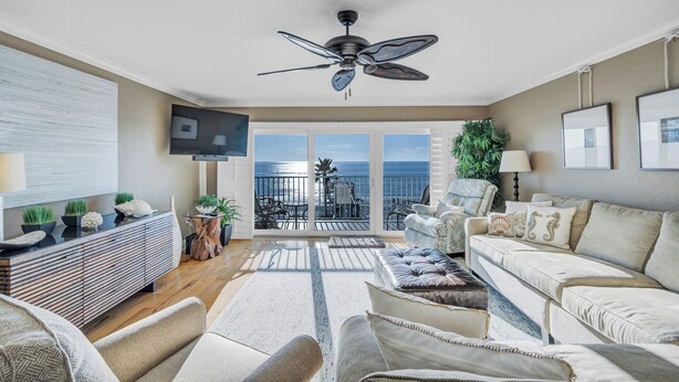 A spacious living room with a ceiling fan, a sofa set, a TV, and a balcony with a view of the ocean. - Huge 3rd Floor Gulf Front Condo w/ Balcony SD304 (Indian Shores)