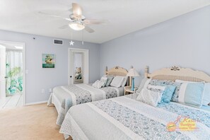 Ein Schlafzimmer mit zwei Betten, einem Deckenventilator und einer Tür zu einem Badezimmer.