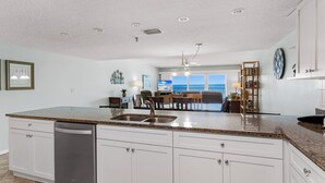 A spacious kitchen with a large island, white cabinetry, and a dishwasher.