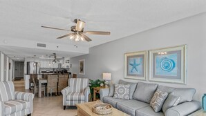 A living room with a grey sofa, striped armchairs, a wooden coffee table, and a ceiling fan. - Spacious Gulf Front Condo w/ Big Balcony - SD310 (Indian Shores)