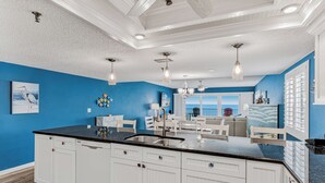 A modern kitchen with white cabinets, a black countertop, and pendant lighting.