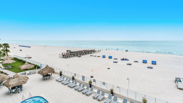 A beach resort with a pool, lounge chairs, and a lifeguard tower.