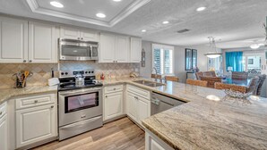 Una cocina moderna con armarios blancos, electrodomésticos de acero inoxidable y encimera de mármol.