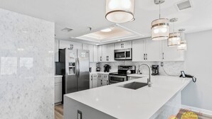Una cocina moderna con armarios blancos, electrodomésticos de acero inoxidable y una isla grande con un fregadero.