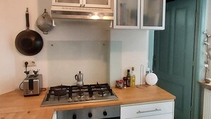 Una cocina con armarios blancos, estufa a gas, horno y lavavajillas.