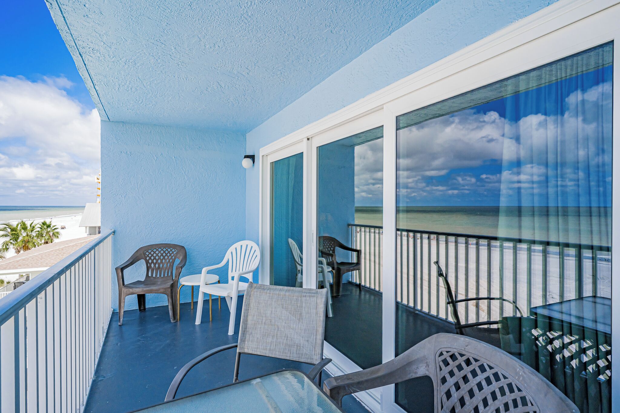 A balcony with a view of the ocean, featuring a table, chairs, and a glass door leading to the interior.