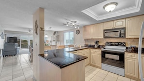 Una cocina moderna con una isla central, microondas, horno y zona de comedor con sillas y mesa.