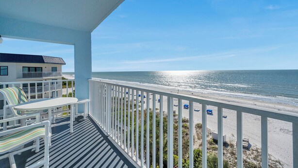 A balcony with a view of the beach and ocean.