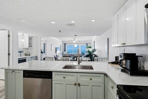 A modern kitchen with white cabinetry, a central island, stainless steel appliances, and a view to the dining area.