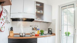A kitchen with white cabinets, a black oven, and a countertop with various items.