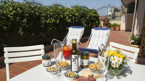 A table set outdoors with food, drinks, and a bottle of wine.