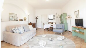 A living room with a sofa, a dining table, and a TV stand.