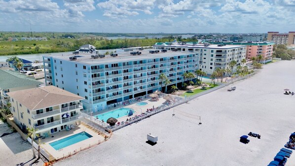 A hotel with multiple floors, a swimming pool, and a beach area.
