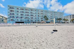 Un hôtel situé en bord de mer, doté de nombreux balcons, d’une plage de sable fin et offrant une vue sur un ciel dégagé.