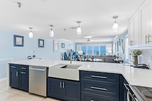 A modern kitchen with a large island, built-in appliances, and a view to the outside.