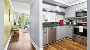 Une cuisine moderne dotée d’appareils électroménagers en acier inoxydable, de meubles de couleur grise et d’un plancher en bois.