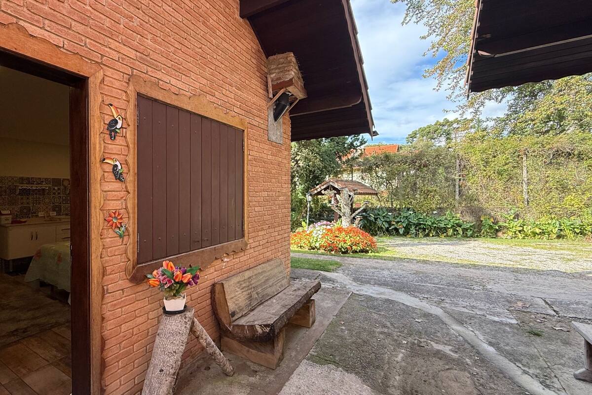 A rustic brick building with a wooden bench and a small table with flowers.