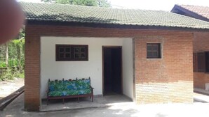 A small brick building with a tiled roof, a bench outside, and a door leading inside.