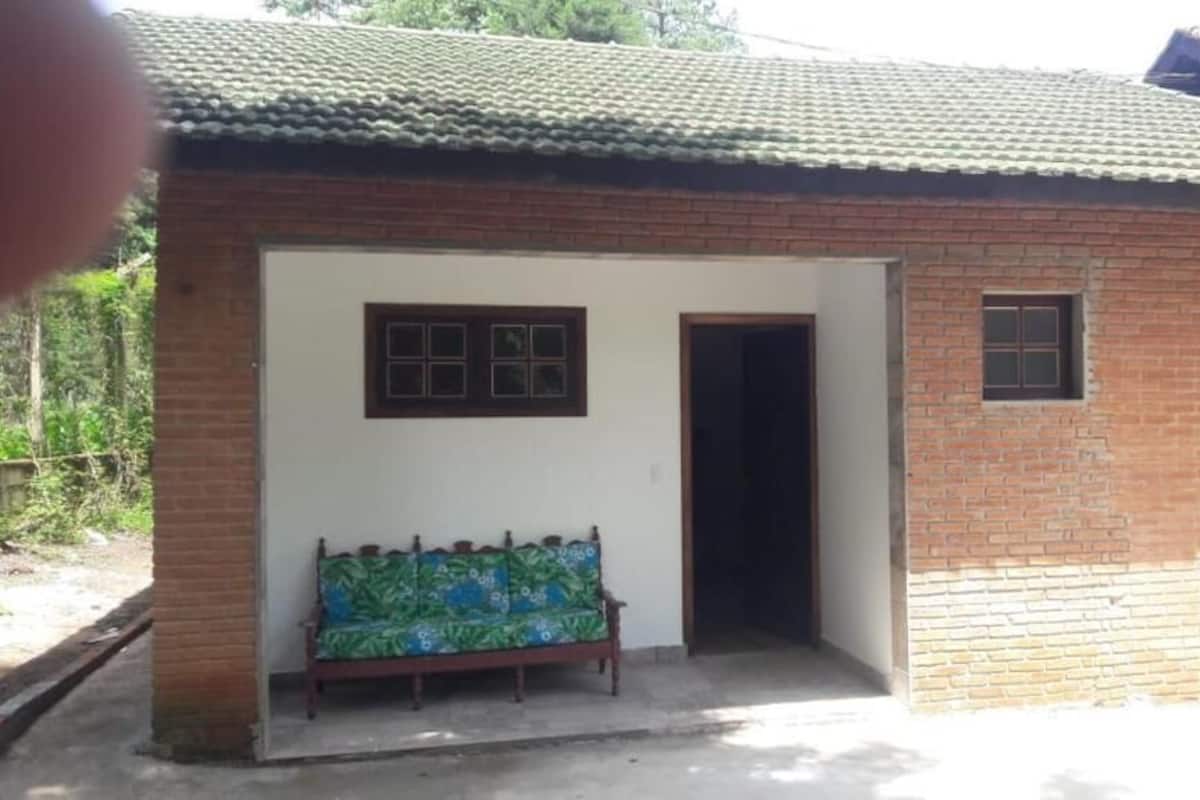 A small brick building with a tiled roof, a bench outside, and a door leading inside.