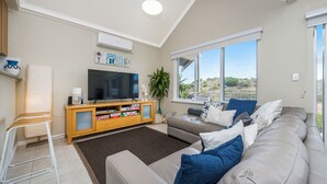 Ein Wohnzimmer mit Fernseher, Sofa und Barhocker.
