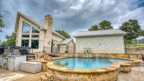 A modern house with a large stone exterior, a swimming pool, and outdoor furniture. - Family-Friendly 4BR on 5 Acres • Pool, Big Porch (Burnet)