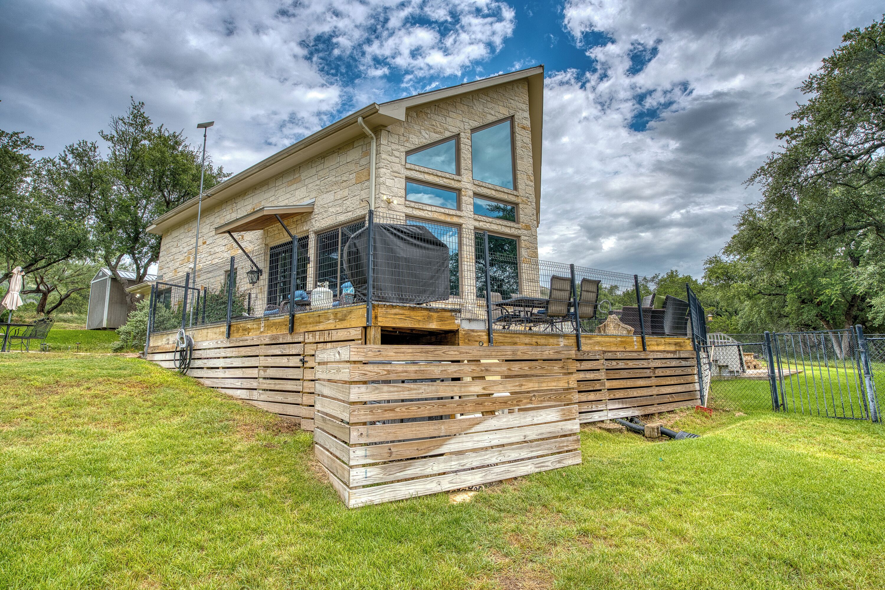 A modern house with a stone facade, large windows, and a wooden deck.