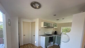 Una cocina compacta con estufa a gas, horno y cafetera.