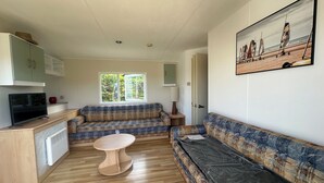 Una sala de estar con un sofá, una mesa de centro, un televisor y un cuadro de veleros.