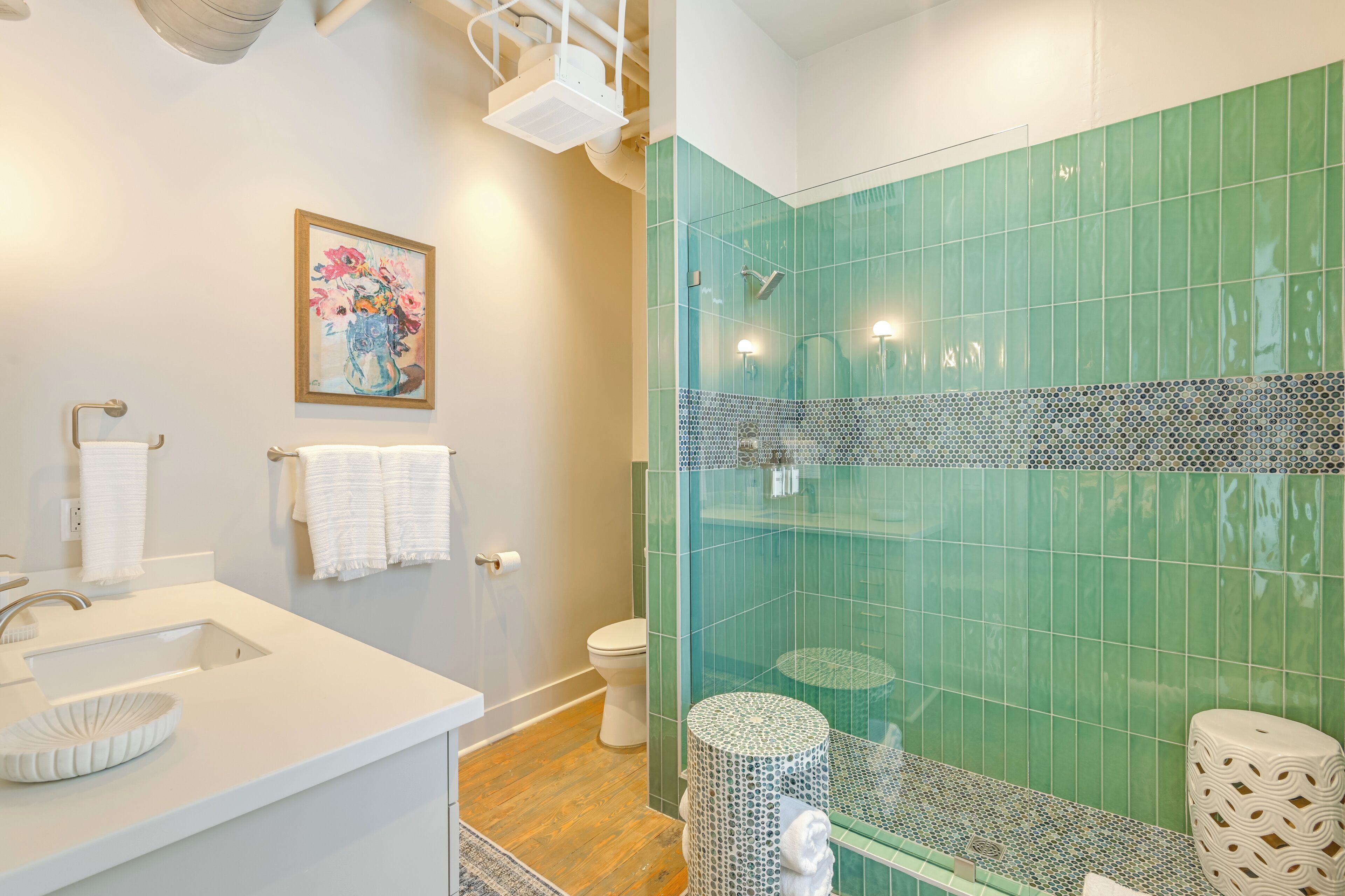 A modern bathroom with a glass shower enclosure, a white sink with a decorative bowl, and a toilet.