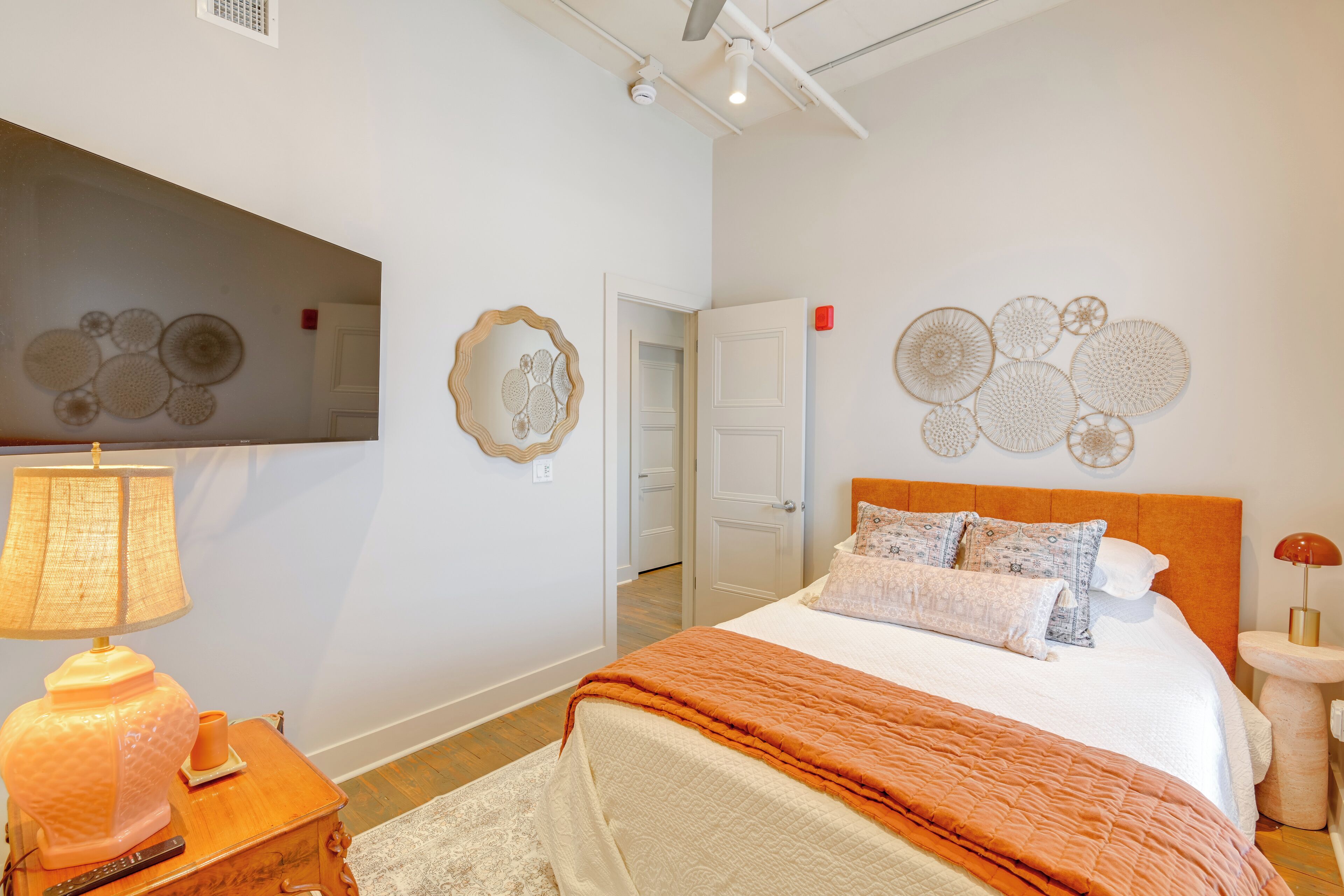 A bedroom with a bed, a bedside table with a lamp, and wall art.