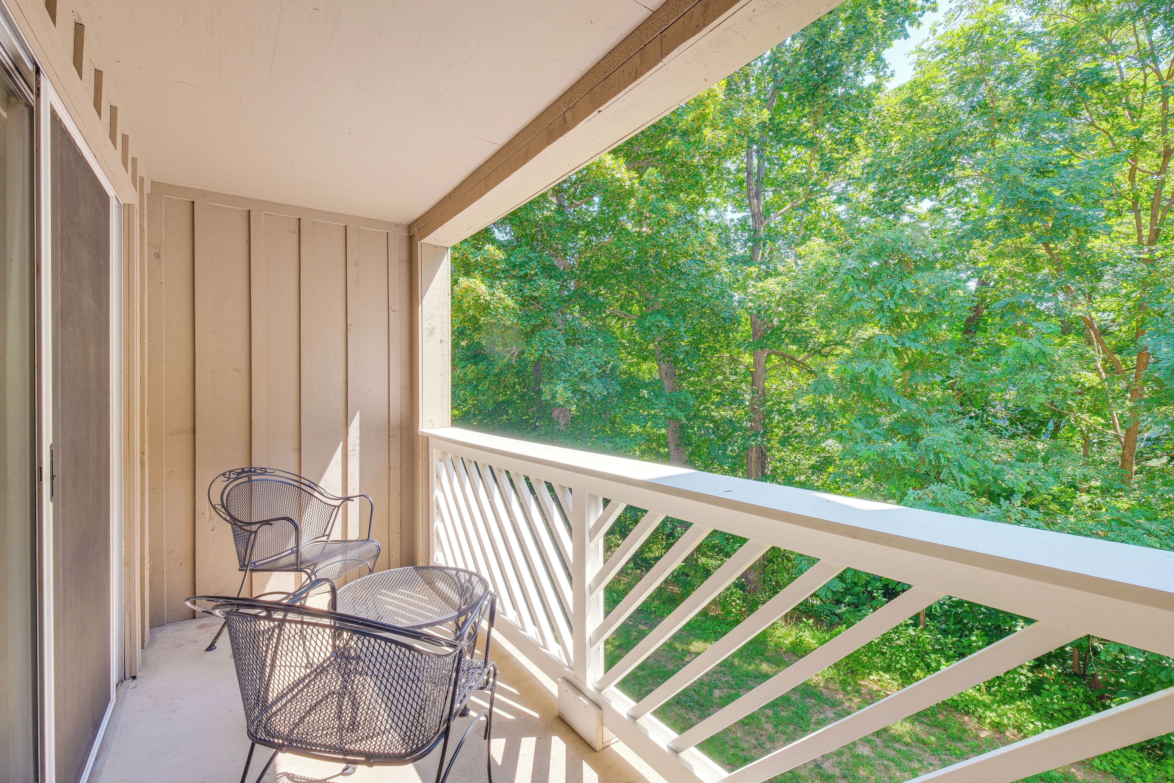 A balcony with a white railing, two metal chairs, and a small table.