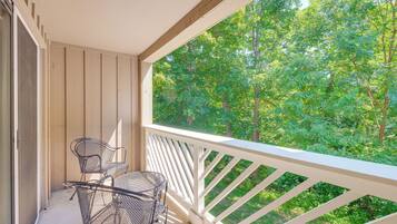A balcony with a white railing, two metal chairs, and a small table.