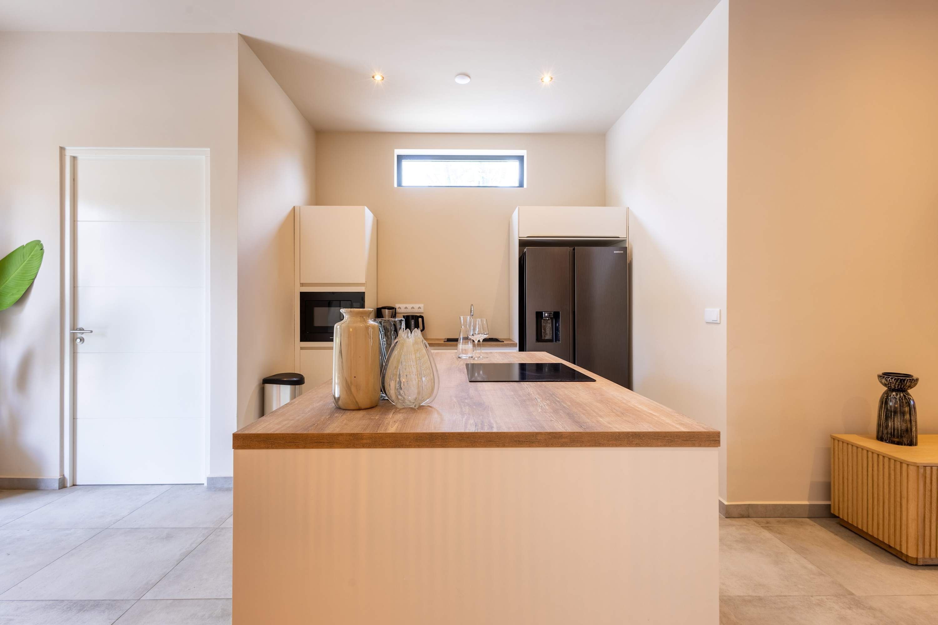 Una cocina moderna con una isla central, electrodomésticos integrados y un pequeño ventanal sobre el fregadero.