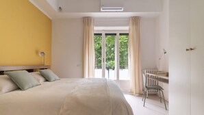 Un dormitorio con una cama grande, un escritorio y vistas a zonas verdes.