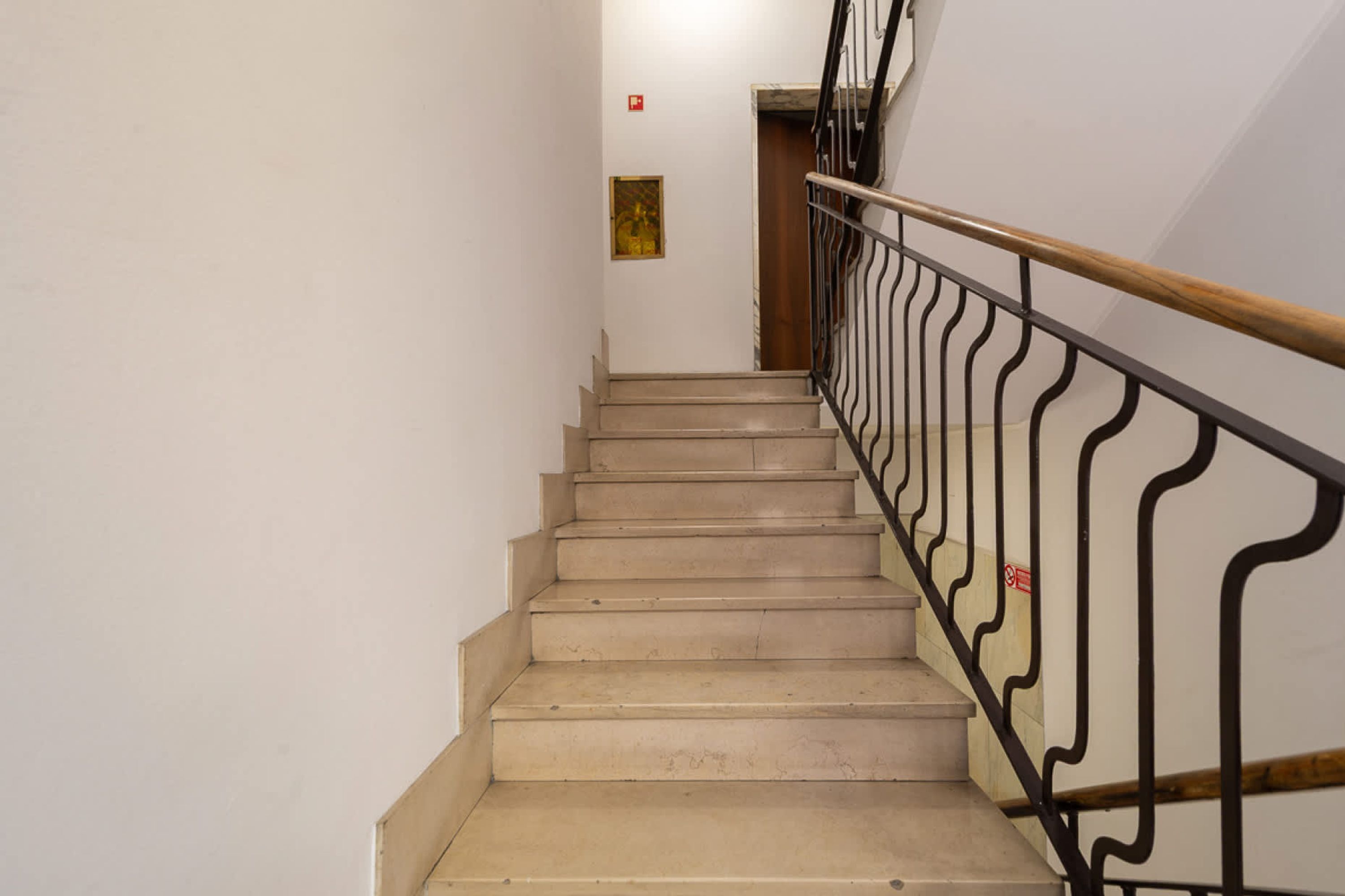 A staircase with beige steps and a black metal railing.