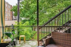 A balcony with a wicker sofa, a small table, and a potted plant. - Walk to Washington St: Hoboken Apt w/ Balcony! (Hoboken)