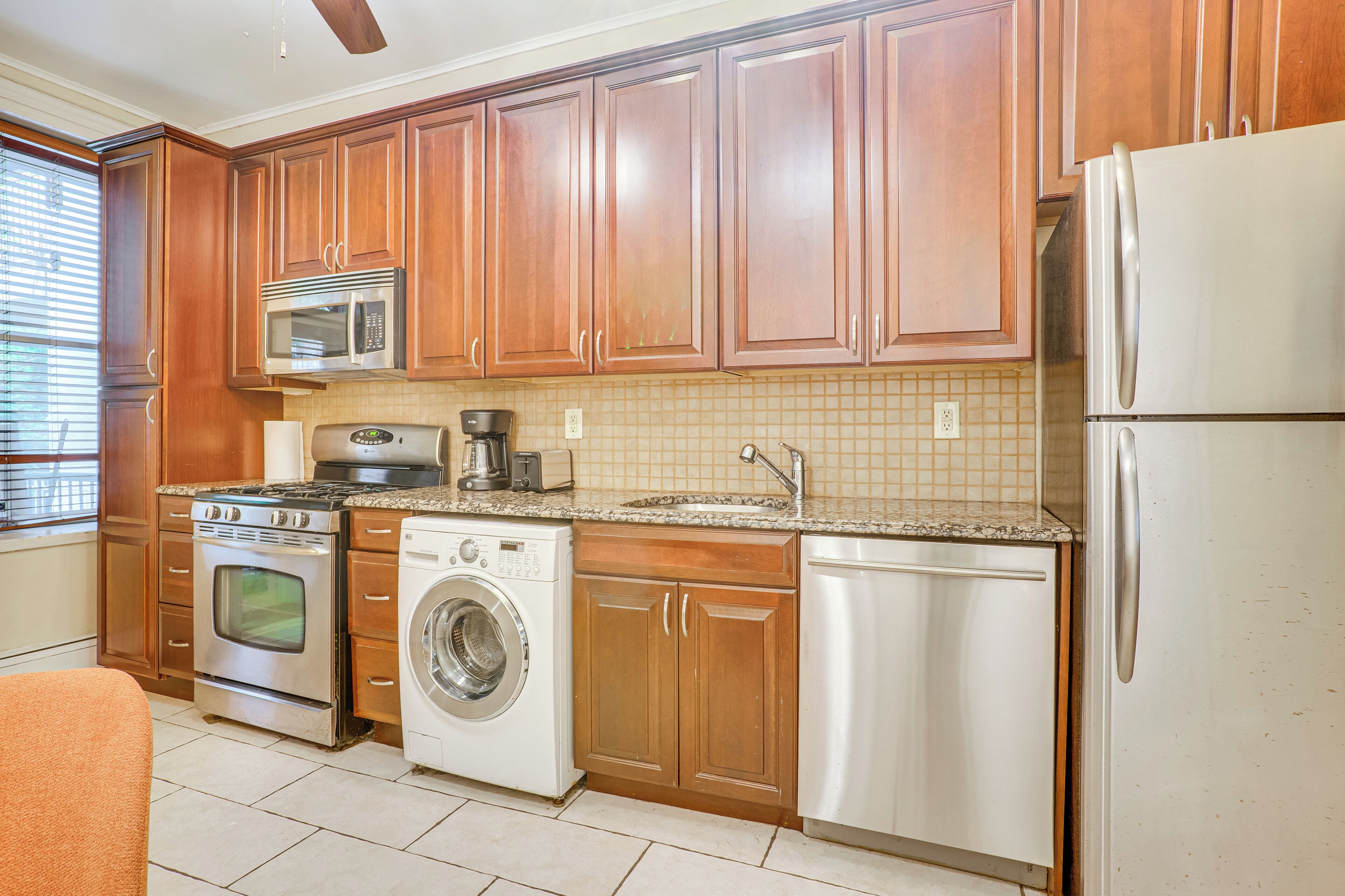 Una cocina con armarios de madera, electrodomésticos de acero inoxidable, lavadora y refrigerador.
