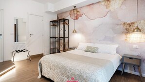 Un dormitori amb llit, una banca, un armari i una paret amb un disseny texturat.