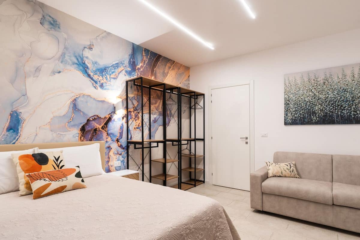 A modern bedroom with a large bed, a built-in wardrobe, and a painting on the wall.