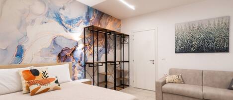 A modern bedroom with a large bed, a built-in wardrobe, and a painting on the wall.