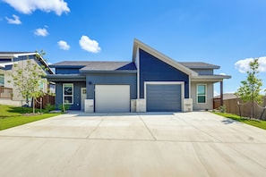 Ein modernes, zweistöckiges Haus mit Garage, überdachter Auffahrt und gepflegtem Rasen.