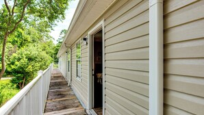 A wooden deck with a white railing, leading to a house with beige siding and a white gutter. - Universities, Parks & More: Getaway in Tallahassee (Tallahassee)