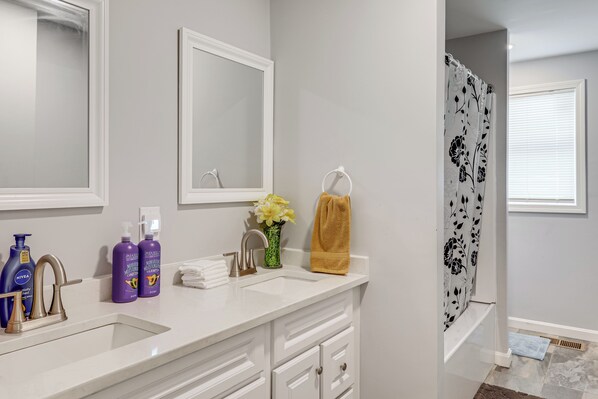 Une salle de bain avec un meuble-lavabo blanc, un miroir, un lavabo et un rideau de douche.
